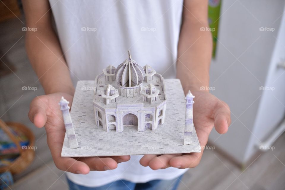 модель мечети  из бумаги в руках подростка