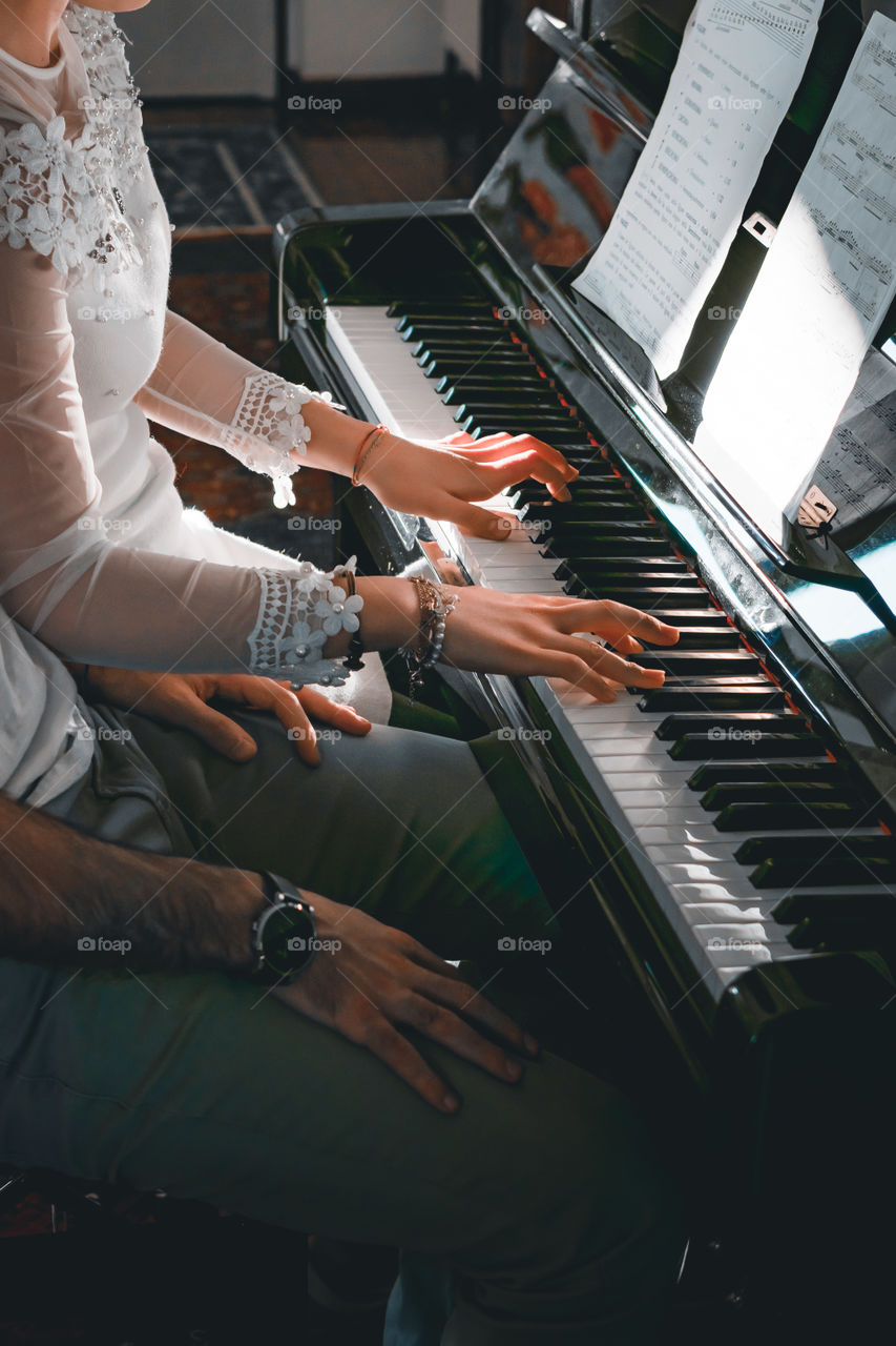 Girl teaches a pupil to play the piano