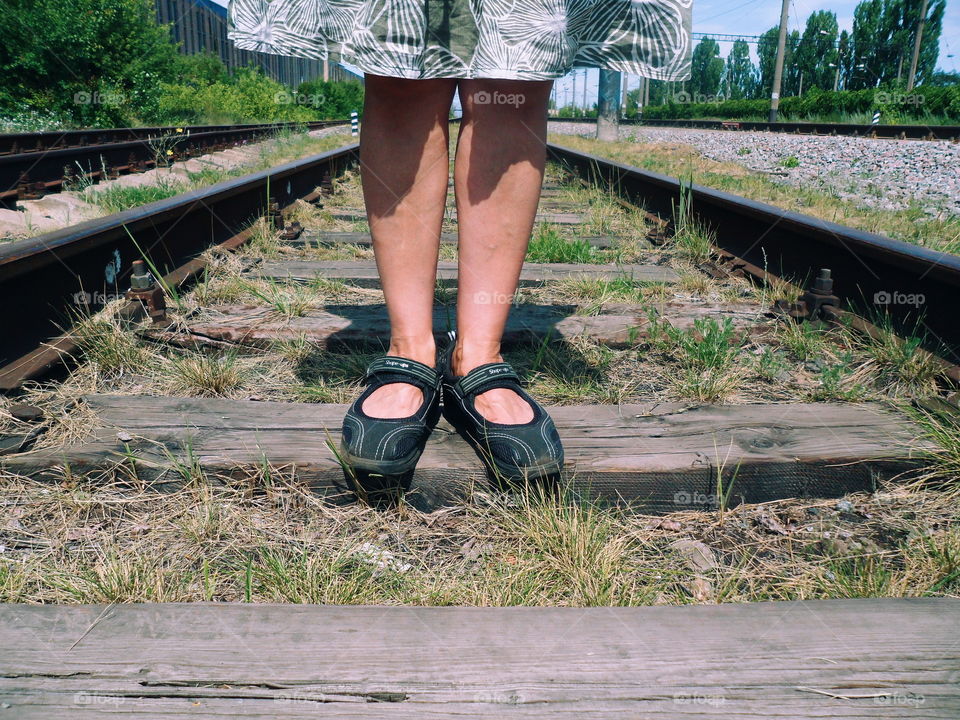 The girl is standing on the tracks