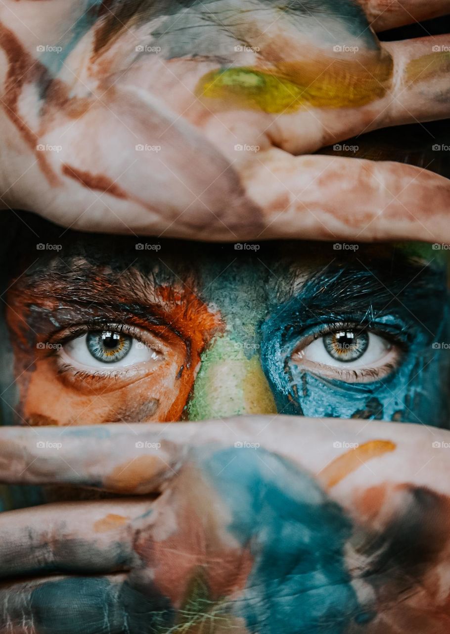 Close-up of eyes looking through hands .