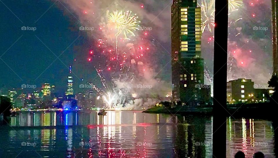 One of several launching sites for these magnificent fireworks can be seen downstream on the “East River” at “Newtown Creek”. In the distance there is the famous “Empire State Building” and the “Manhattan skyline”. 2022. Hypnotic Productions