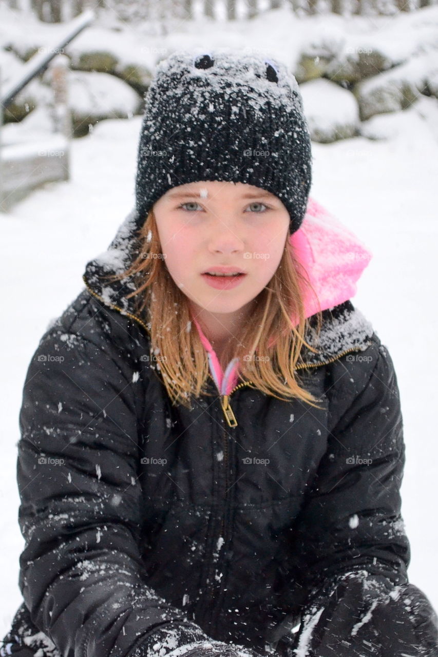 Girl sitting in snowy landscape with warm clothing