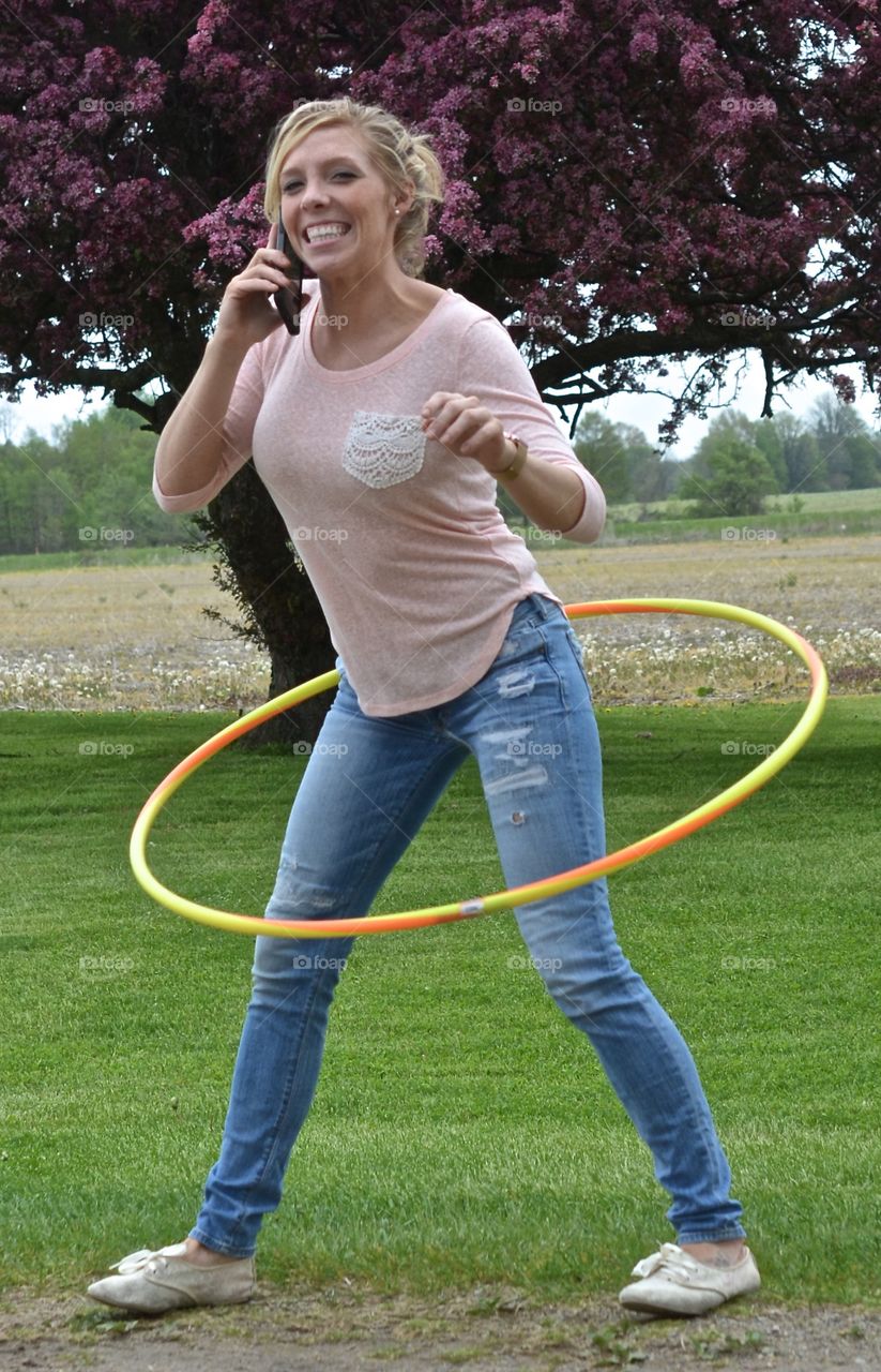 Woman playing hula hoop while using cell phone