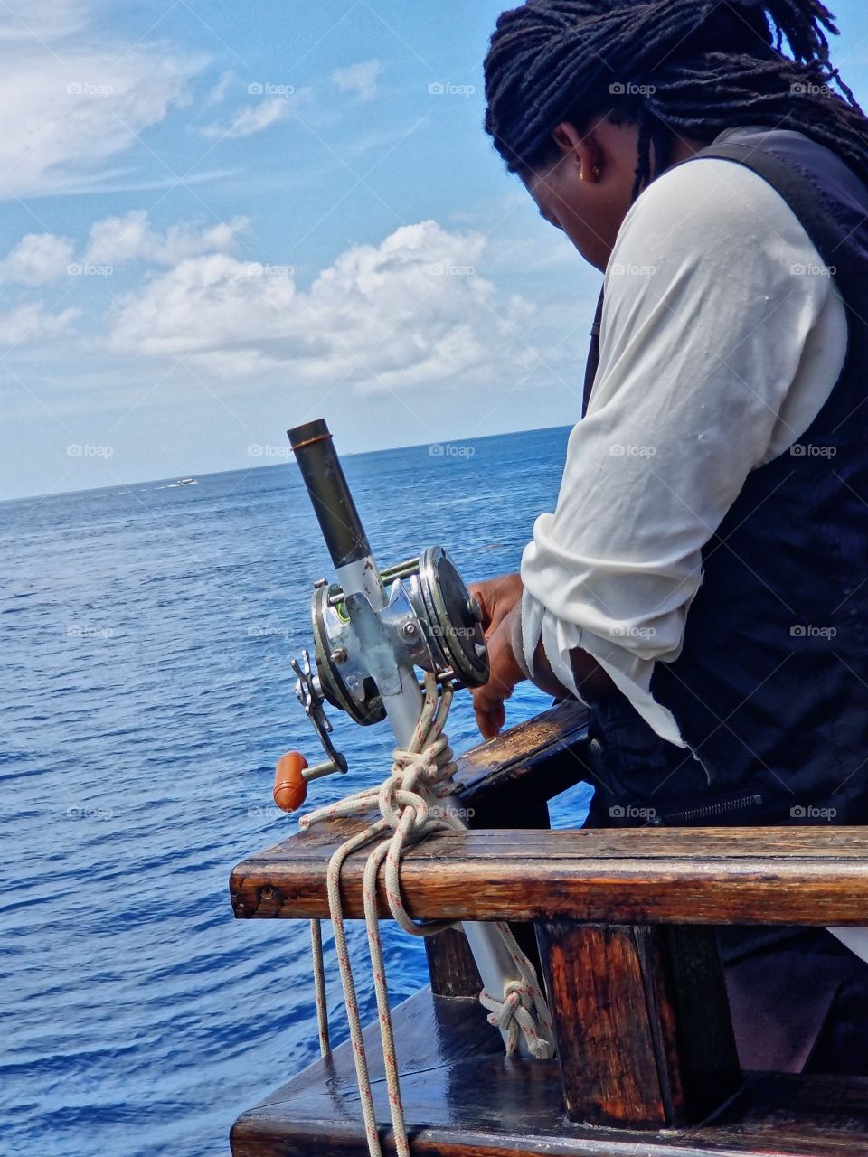 Islander checking fishing line that drags alongside the pirate ship