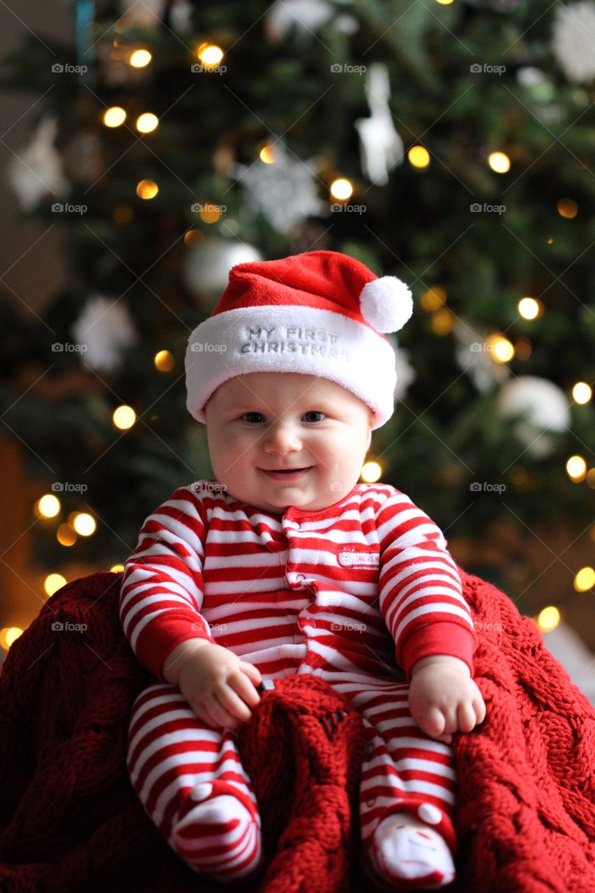 Cute baby sitting front of christmas tree