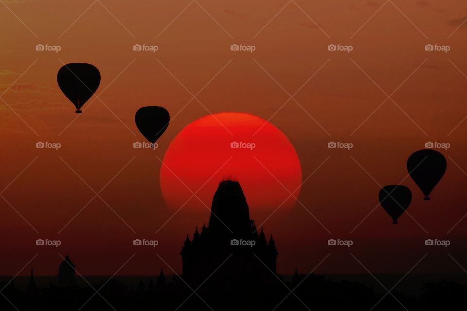 Silhouette balloon float over sunset and pagoda background