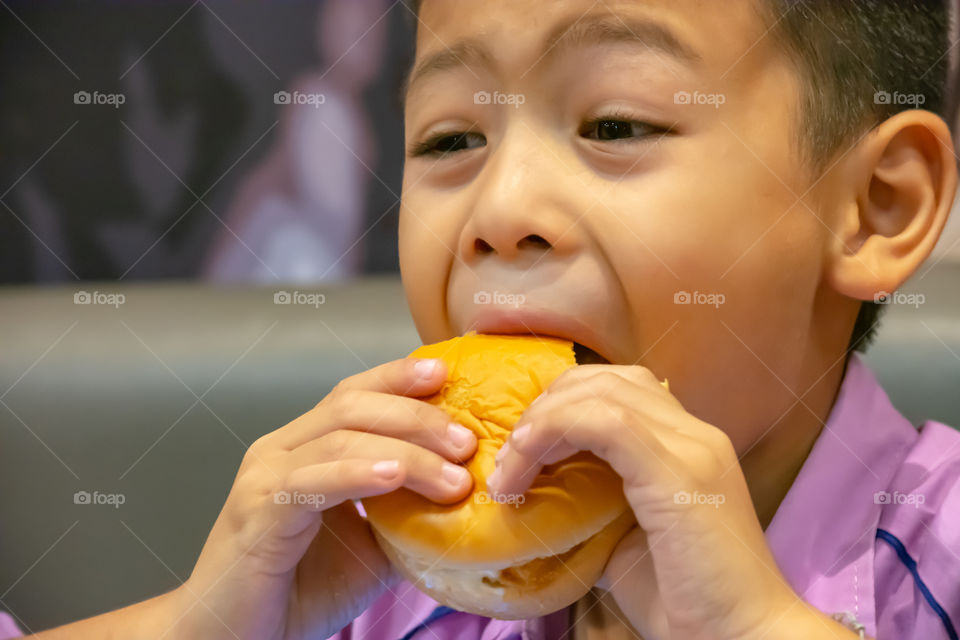 Hamburger fish in hand asia boy holding the eating.