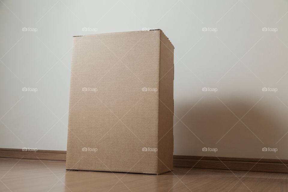 Cardboard box with order placed on the floor in an empty room with a neutral background. delivery concept. economy concept. business concept. shopping concept. copy space. Nobody