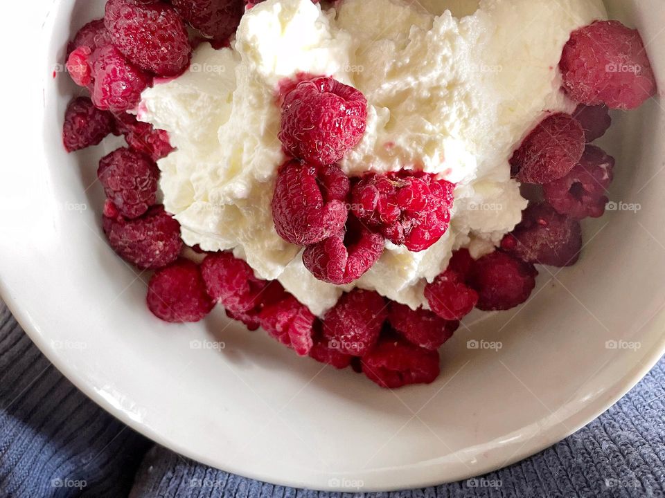 Close-up of raspberries on yogurt in a white bowl