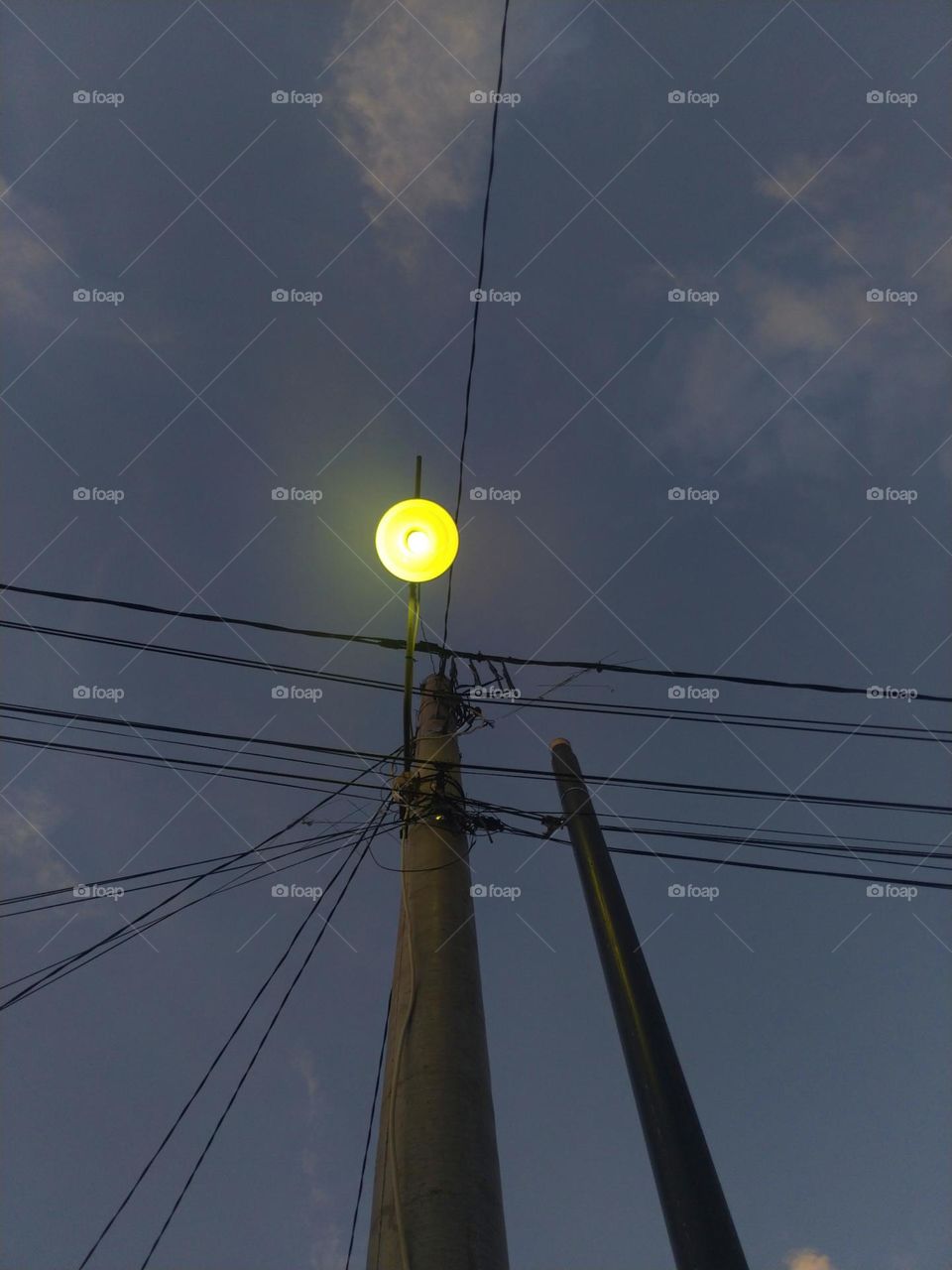 electricity pole with one lamp that lights up in the evening