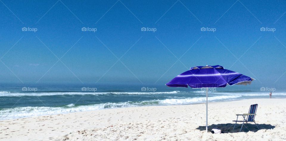 Ah mar... amar... Céu azul e uma cadeira na sombra de um guarda sol.