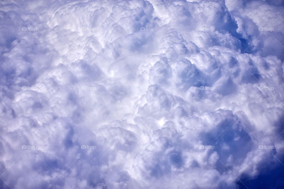 white fluffy clouds on the blue sky from plane window