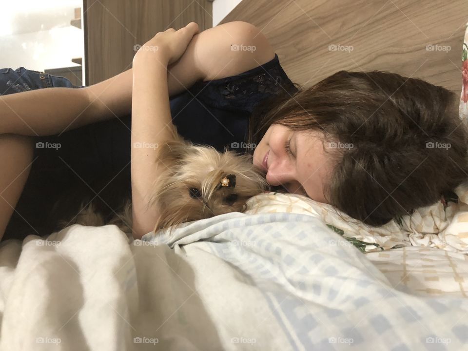 Jovem e cachorro Yorkshire na cama