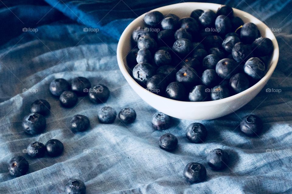 Fruits! - Blueberries in a white bowl and scattered on graduated blue fabric  