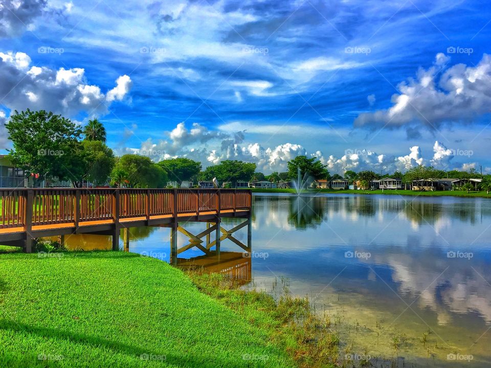 Landscape view of pier and clouds and trees reflecting in lake