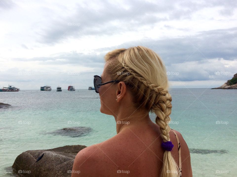 Blonde woman looking at boat in sea