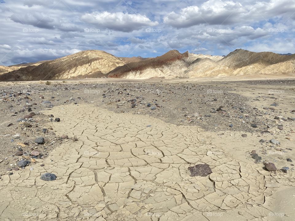 A hike in Death Valley National Park with the painted hills in the background and fluffy clouds in the sky!