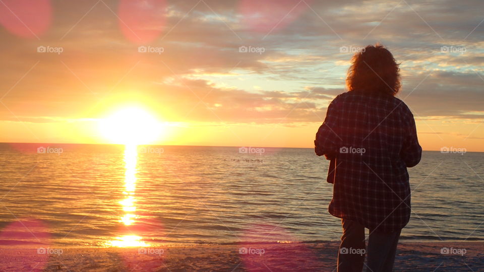Admiring a golden shiny sun as it sets over the horizon Gulf of Mexico