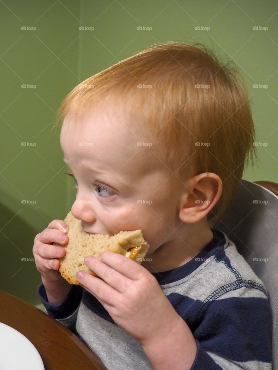 Toddler boy eating his peanut butter and banana sandwich