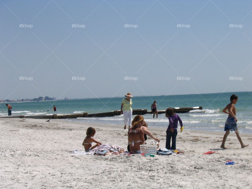 Woman in hat walking beach. Woman in hat walking Florida beach past children and families