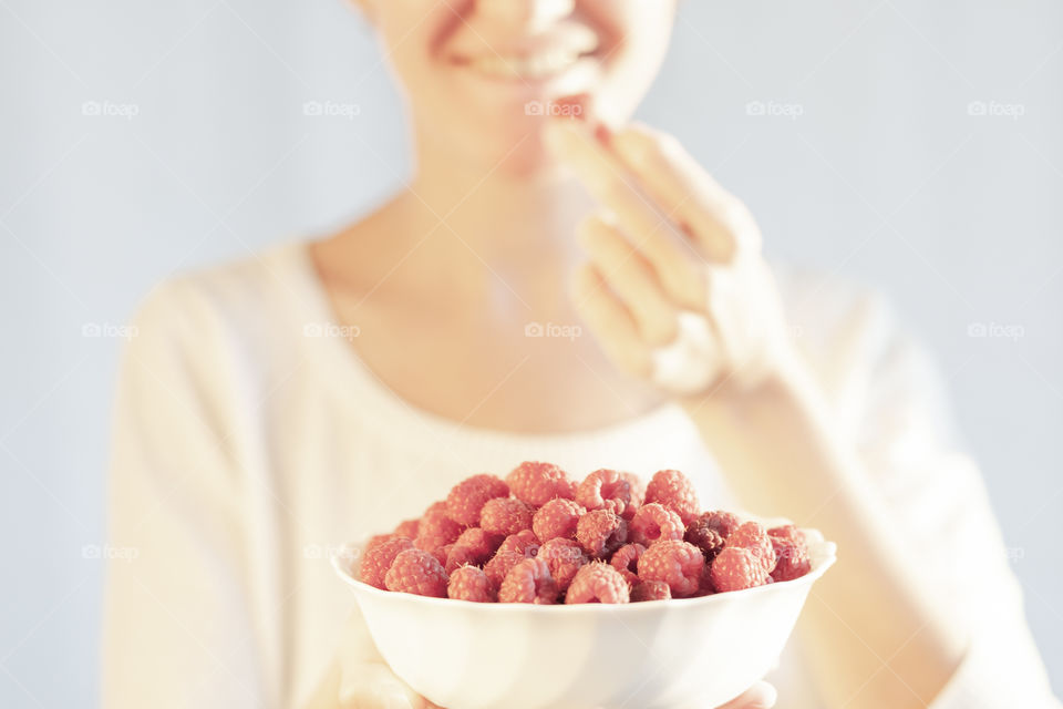 Laughing girl eating raspberries