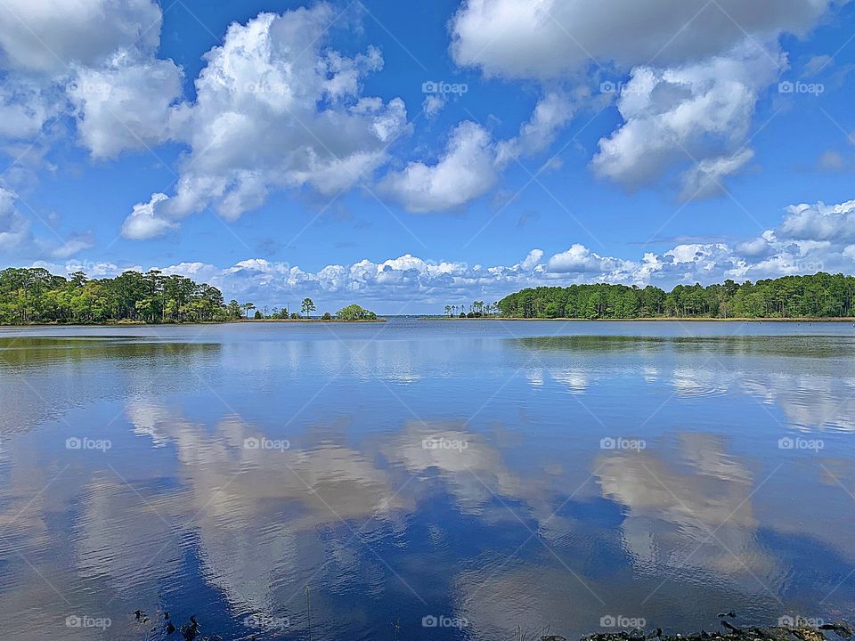 Bright blue sky with floating puffy clouds over an open waterway. The effects of weather on our moods and emotions depends on our behavior and on how we think. The sun may melt our hearts. In rainy days people have lower satisfaction in their lives. 