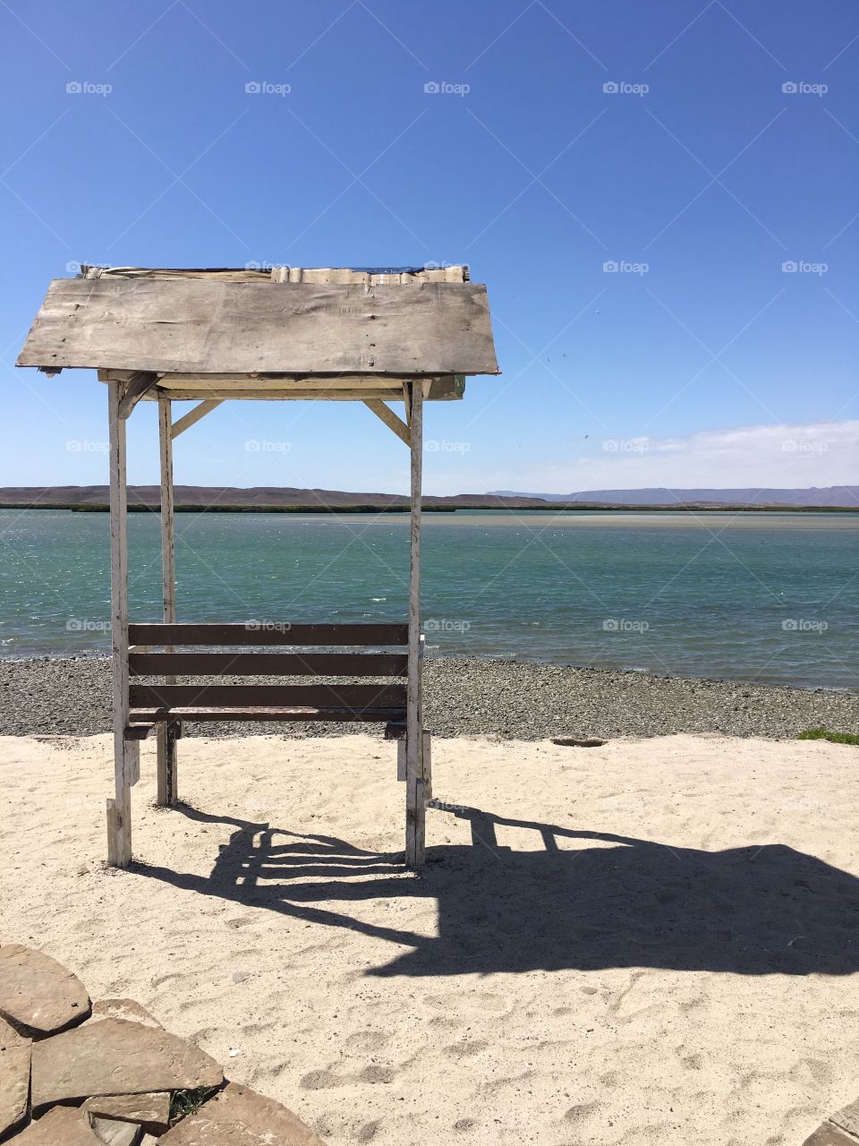 A quiet bench overlooks the ocean in a clear blue sky day