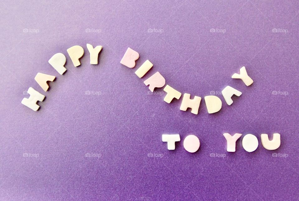 Happy birthday! A message spelled out using candy letters on a purple background. 