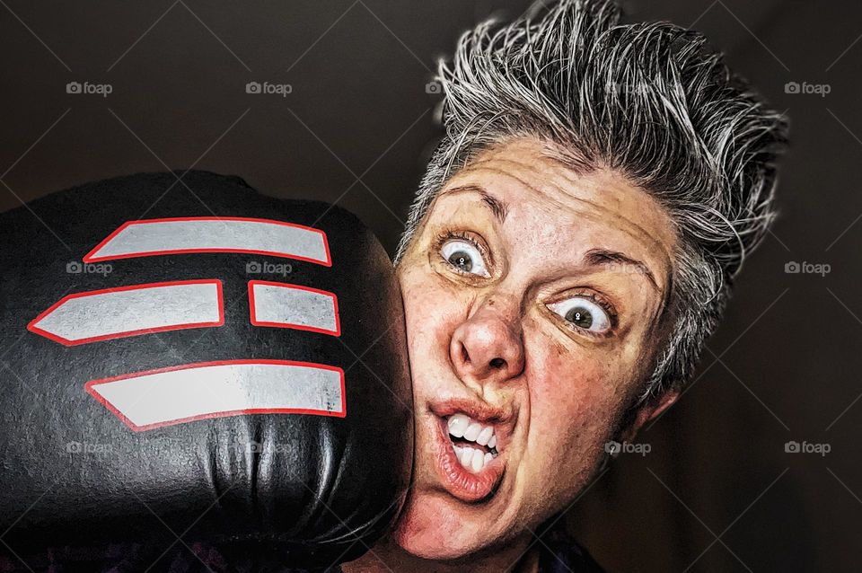 Woman getting hit in the face with a boxing glove, woman surprised by boxing glove hit, hit in the face, look of surprise on woman’s face as she gets hit with a boxing glove, surprised facial expression on woman, boxing glove portrait