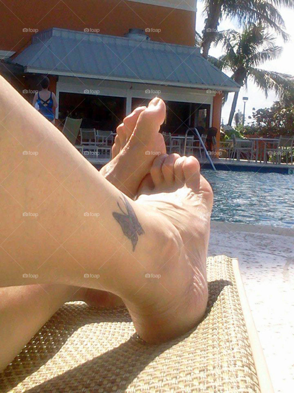 relaxing by the  pool. crossed ankles with tattoo poolside