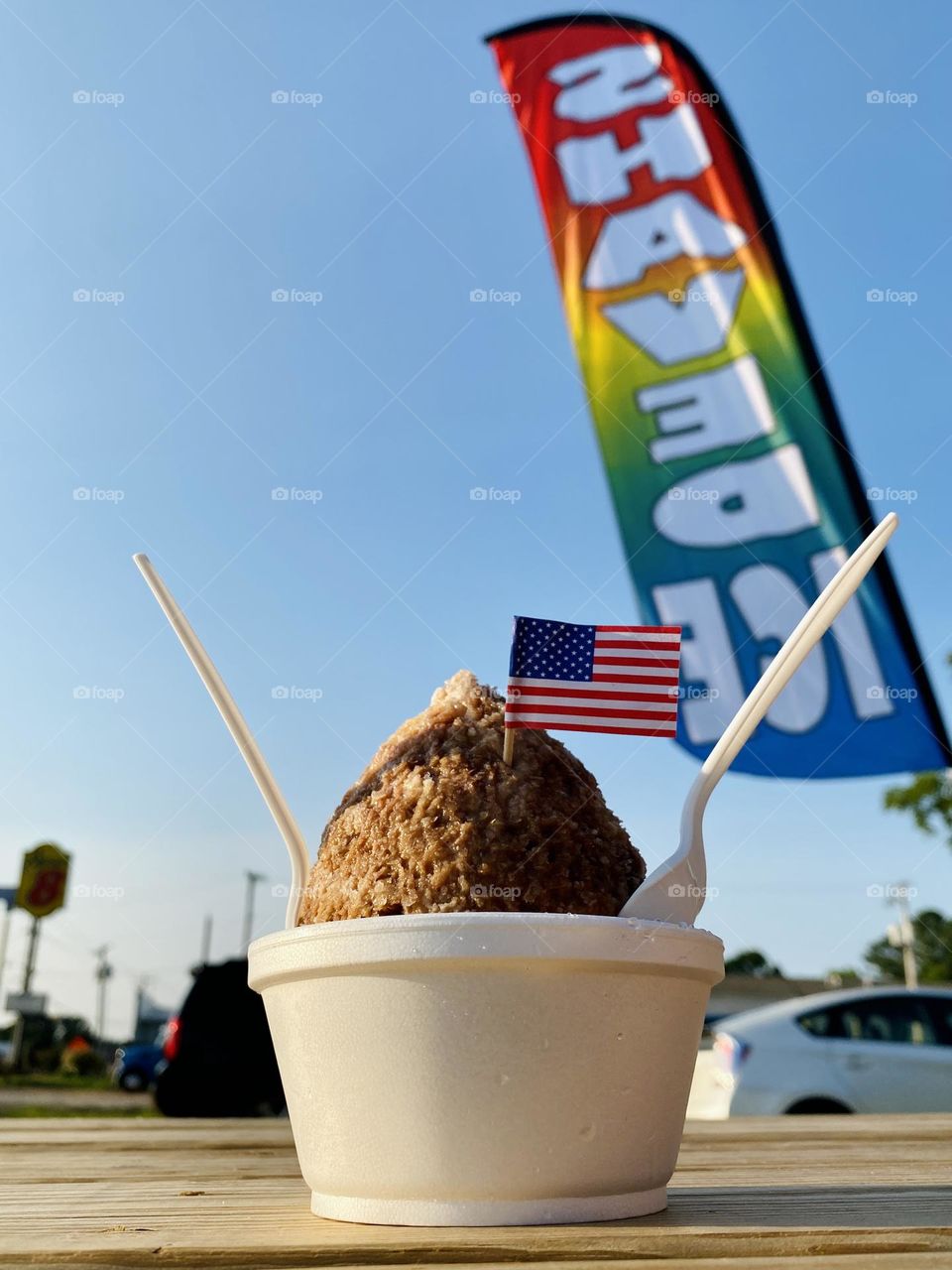 A rainbow sign fills the background of a shaved ice dessert