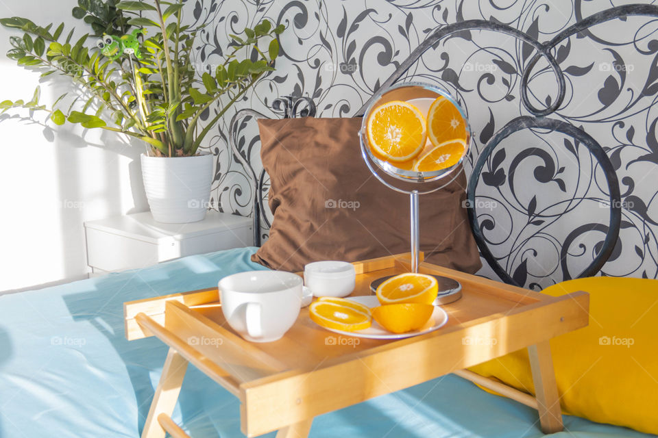 A man and home spa care at home takes care of himself and smears his face with cream, does a manicure at home on a blue background and with oranges and rests.