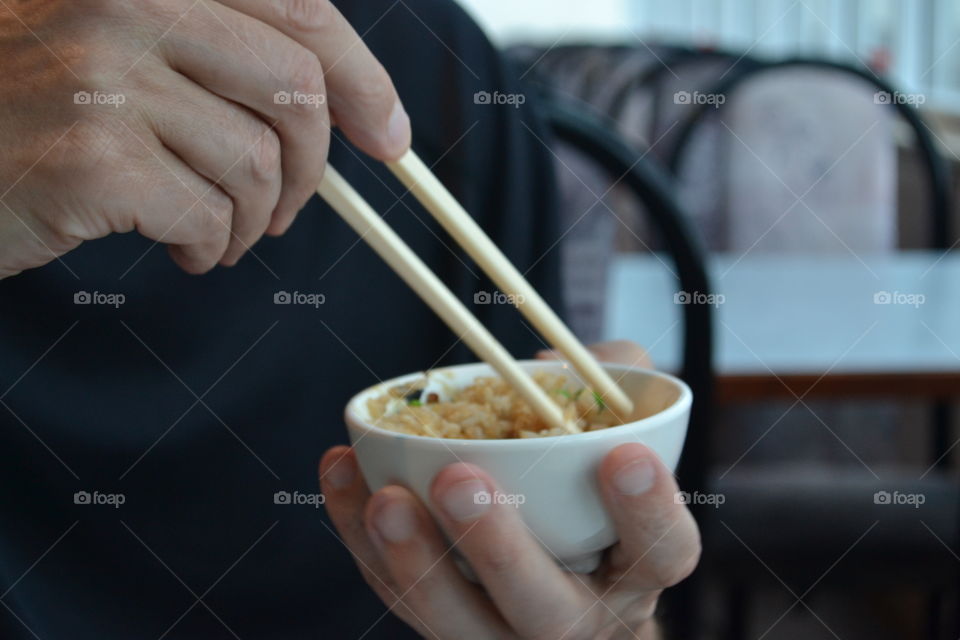 Closeup person eating Chinese food in bowl with chopsticks