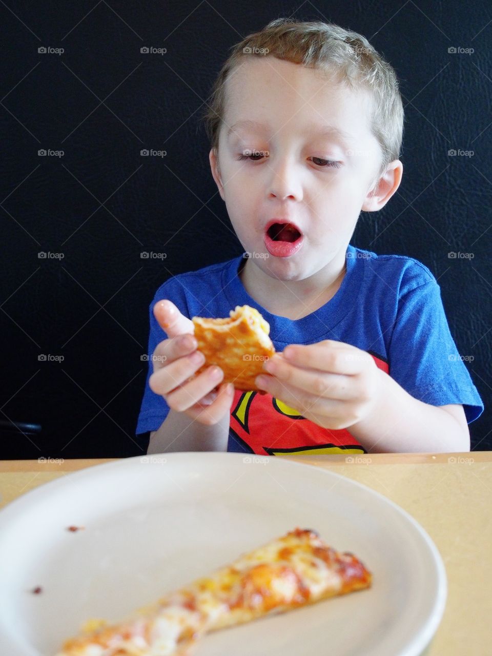 A little boy gets a surprise when biting off a piece of pizza that turns out to be very hot!