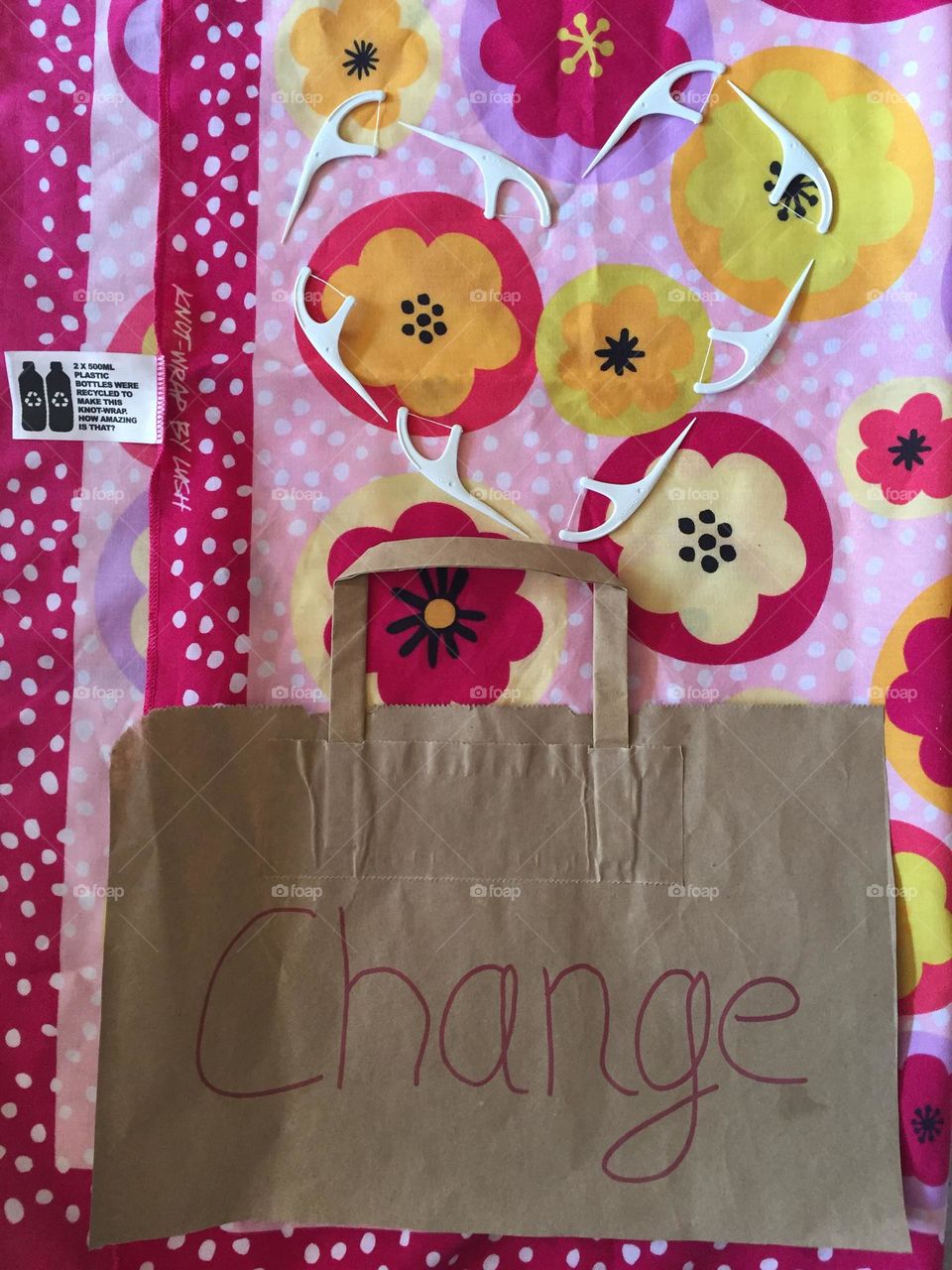 Recycled paper note about change lying on a recycled bottle cloth and a heart of bamboo dental floss