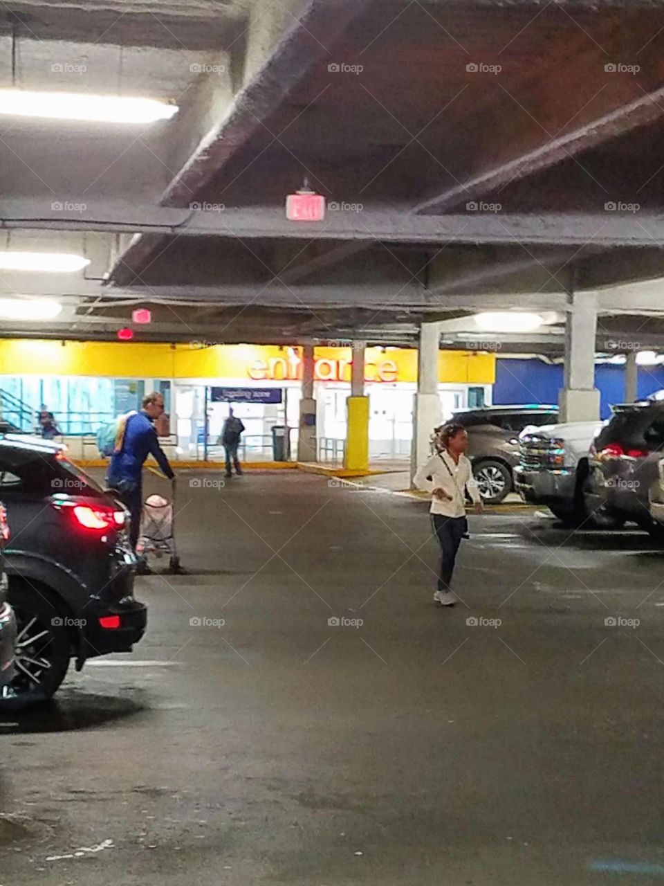 Ground level Entrance doors from parking lot. There are people coming and going to their cars. The Entrance is brightly lit.