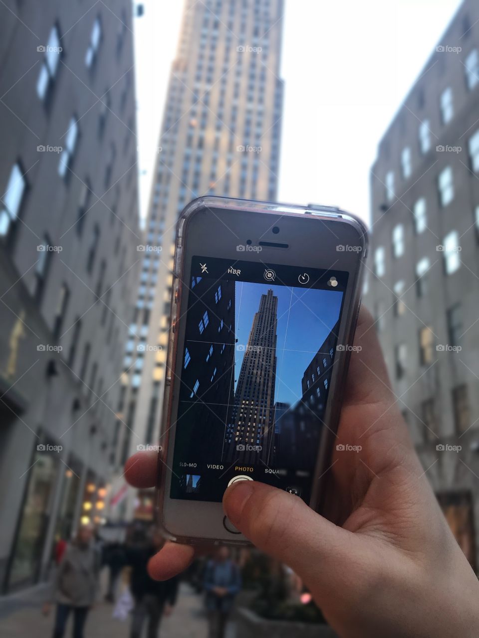 A tall building in New York City, seen from behind a camera screen. A blurred background and a focus on the building in the phone screen. 