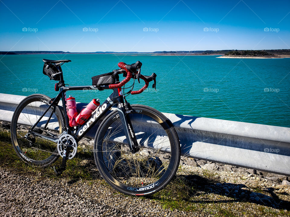 A cyclist taking a break along a route next to a blue lake in the warm Spring weather