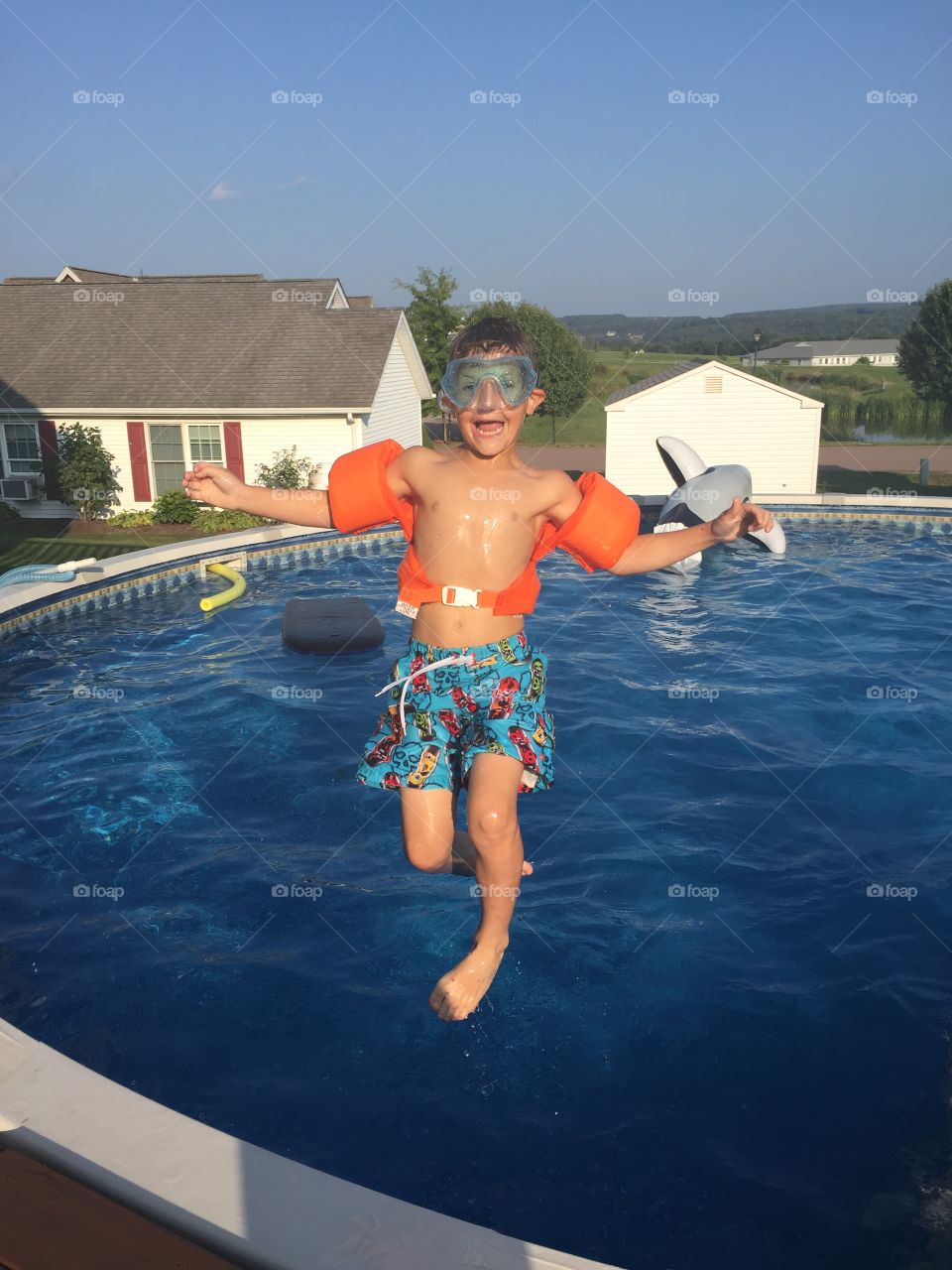 Boy jumping in swimming pool with armband
