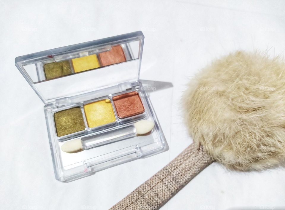 three colours  eyeshadow and fluffy balls isolated on white background