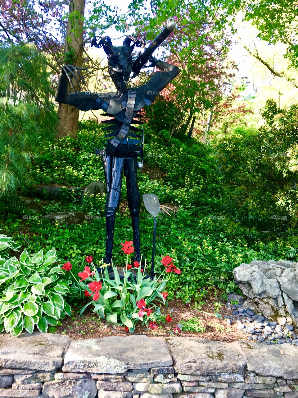 Black Satanic statue In a green garden during spring