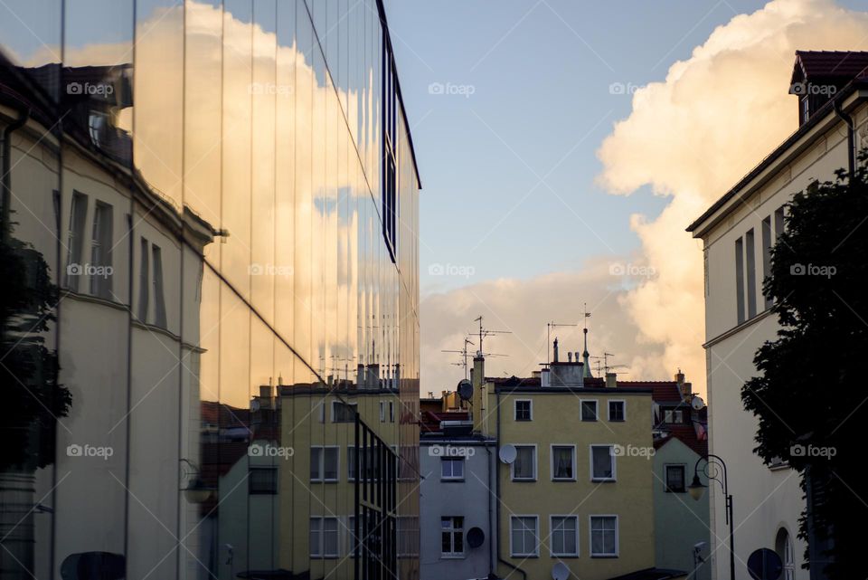 Building with reflective surface in clouds and wild houses