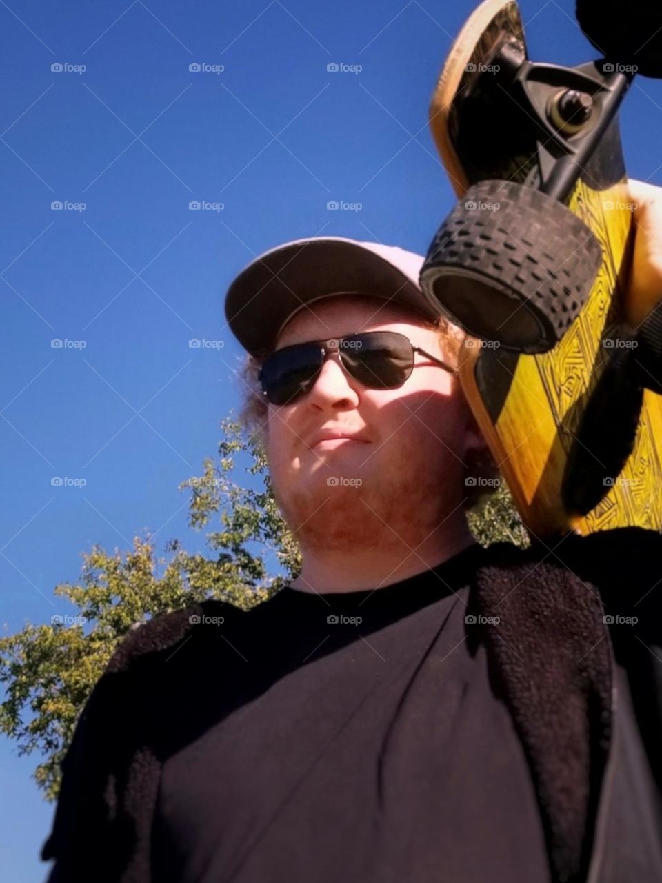 Man holding a Long Board on his Shoulder Outside