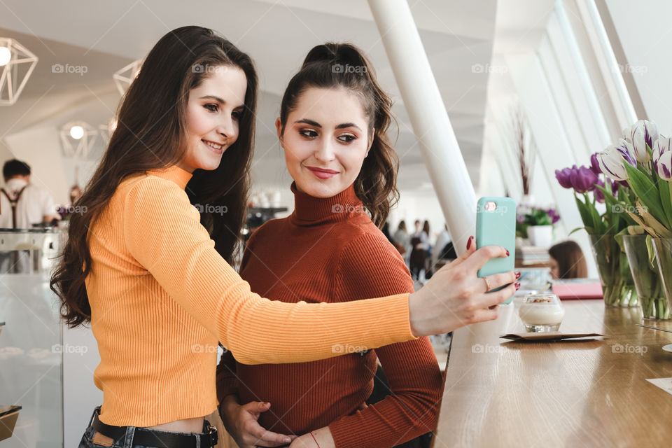 two happy women are photographed on the phone