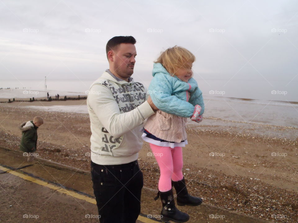 Father holding her daughter at beach