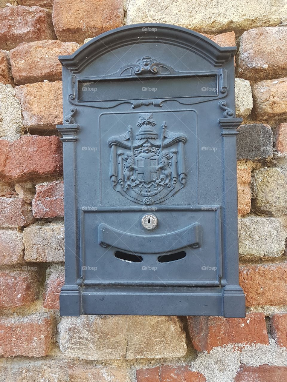 Old grey mailbox on antique brick wall