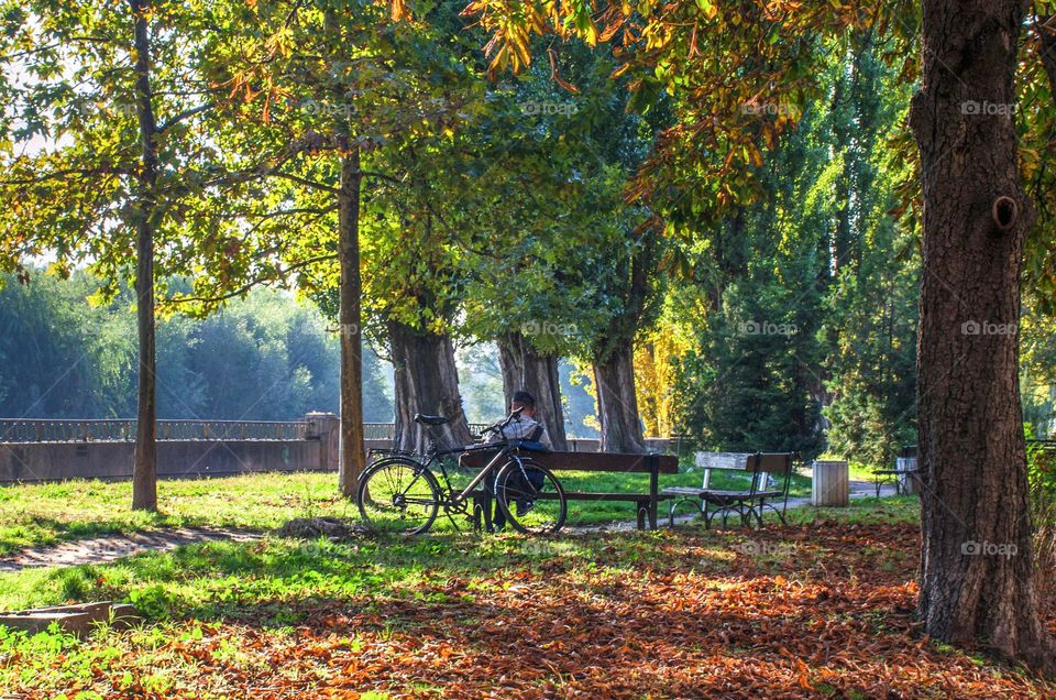 A man with a bicycle rests in the park, on autumn background