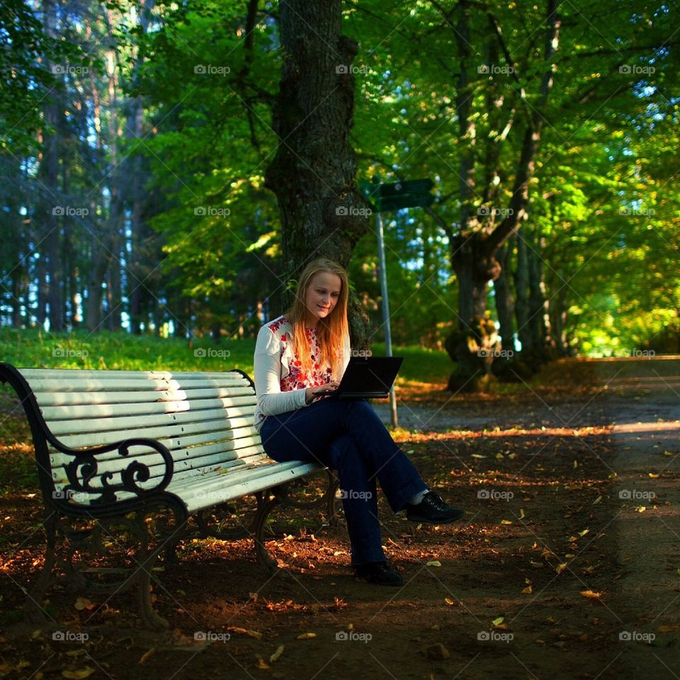 People. Girl in the park working at a laptop