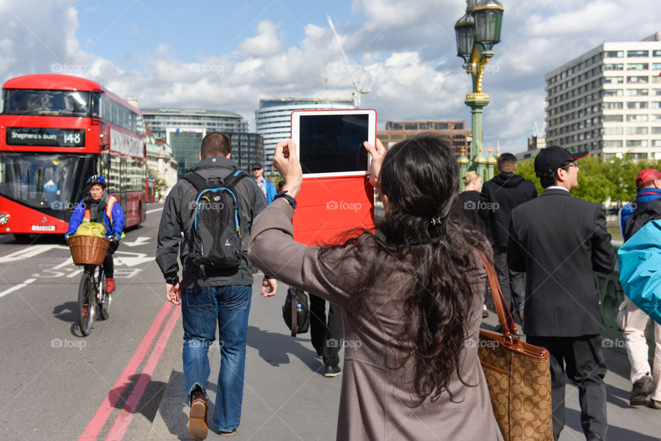 A tourist from Asia using her Ipad to take pictures of Big Ben in London.