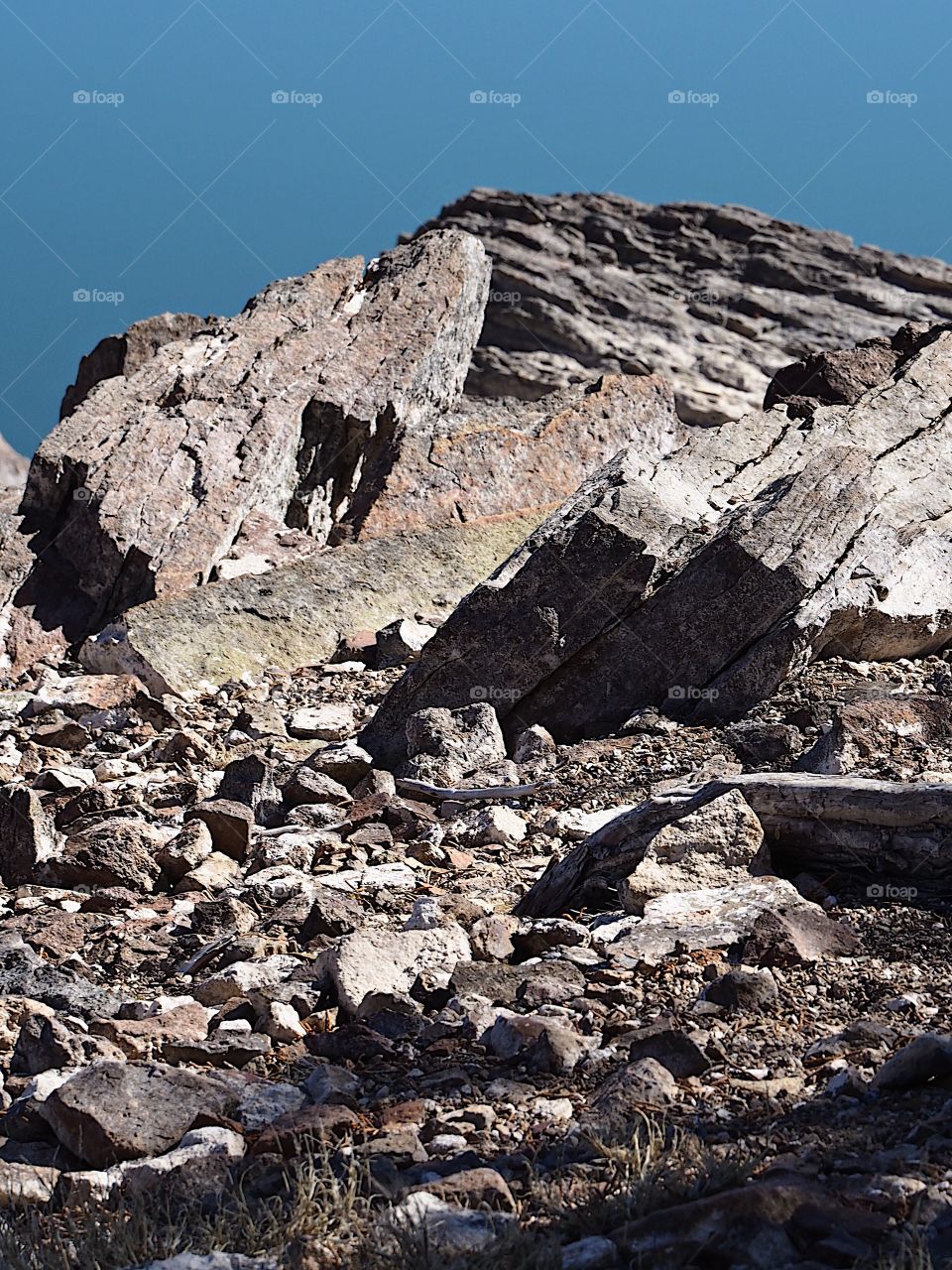 Jagged rocks and boulders along the shoreline of Ochoco Lake in Central Oregon on a sunny spring day.